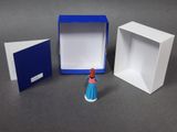 a small figurine of a woman in a blue dress next to a white box