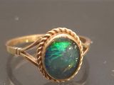 an image of a gold ring with a green oplite in the center