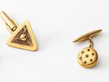 two pairs of gold cufflinks and a pair of earrings on a white surface