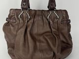 un sac à main en cuir marron posé sur une surface blanche