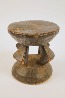 une image représentant un tabouret en bois posé sur une surface blanche