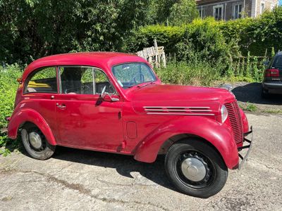 une voiture rouge garée sur un parking à côté d'un immeuble