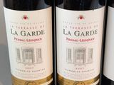 three bottles of red wine are lined up on a table