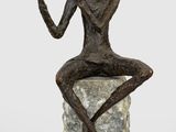 statue of a man sitting on a rock playing a flute