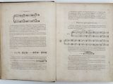 an open book with a page of music in it on a white surface