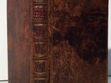 an old book with a brown cover sitting on top of a white table
