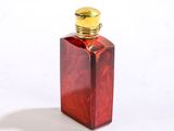 une petite bouteille en verre rouge avec un bouchon doré