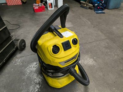 a yellow vacuum cleaner sitting on the floor in a garage