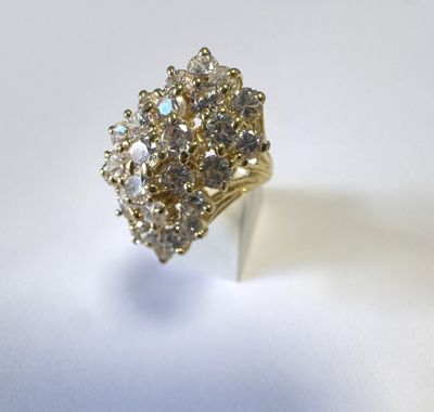 gros plan d'une bague en or avec des diamants sur une surface blanche
