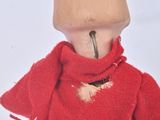 a wooden doll wearing a red sweater and scarf