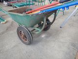 a green wheelbarrow with a bunch of tools in it