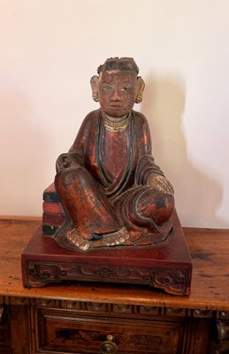 une statue représentant un homme assis sur une table en bois