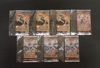 six paquets de cartes à jouer dans des sachets en plastique, posés sur une surface noire
