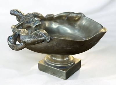 a metal bowl with a bird on it on a pedestal