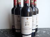 six bottles of red wine are lined up on a table