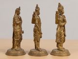 three antique brass figurines of a man and woman on a table