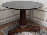 une table ronde avec un piètement en bois dans une pièce
