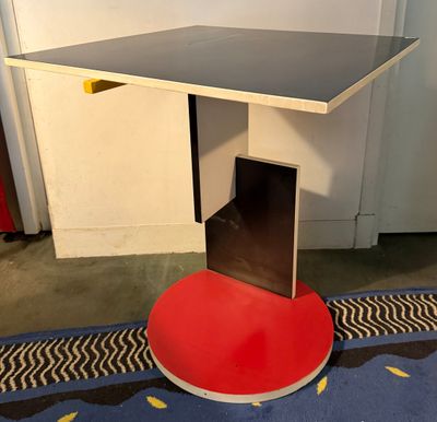 une table rouge avec un plateau noir posée sur un tapis bleu