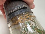 a person holding a glass jar with a painting on it