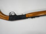 a rifle with a wooden handle on a white surface