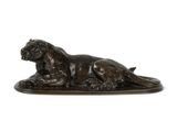 une statue en bronze représentant un chien couché sur un fond blanc