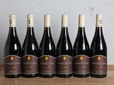 six bottles of wine are lined up on a wooden table