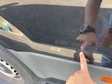a man that is pointing at the door handle of a car