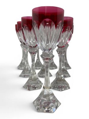 six red wine glasses are lined up in a row on a white surface