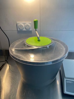 a large metal bowl with a green lid on a kitchen counter