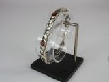 silver bracelet with garnetts on display on a black stand