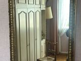 un miroir accroché au mur au-dessus d'une chaise dans une pièce