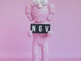 affiche rose représentant un ours en peluche tenant une pancarte sur laquelle on peut lire « Kaws NGV »