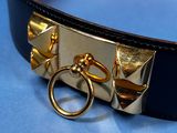 a black belt with a gold buckle on a blue surface