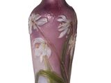 un vase violet orné de fleurs blanches, posé sur une surface blanche