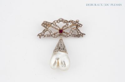a close up of a pearl and diamond broochle on a white surface