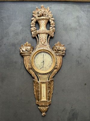 Un baromètre et un cartel en bois doré à décor de corbeilles…