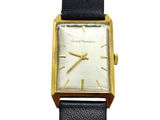 a close up of a watch on a white surface with a black strap