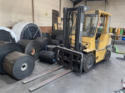 un chariot élévateur garé à côté d'une pile de rouleaux de papier