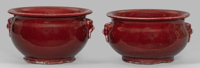 une paire de vases rouges munis d'anses, posés sur une surface grise