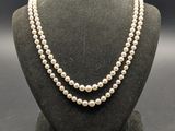 un collier de perles blanches sur un mannequin avec un fermoir en or