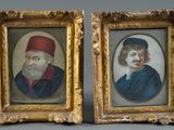 two framed portraits of a man and a woman in red hats
