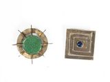 a small metal object with a green stone in it