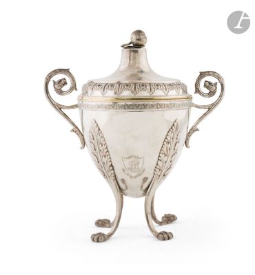 une coupe ancienne en métal argenté, munie d'une anse et posée sur un socle