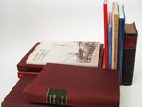 several books are stacked on top of each other on a white surface