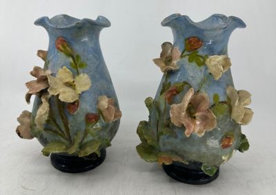 deux vases bleus ornés de fleurs, posés sur une surface blanche