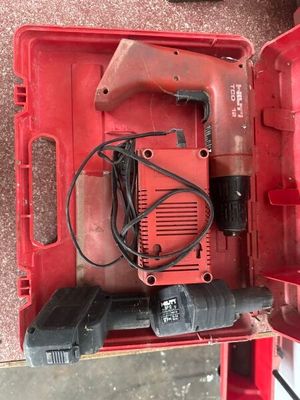 une image représentant une boîte à outils rouge contenant une perceuse filaire et d'autres outils