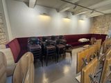 des tables et des chaises dans une pièce avec un mur en pierre et un canapé rouge