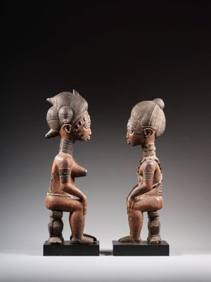 une paire de statues en bois représentant deux femmes assises sur une table