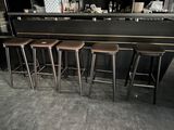 four stools in front of a bar with a black counter top