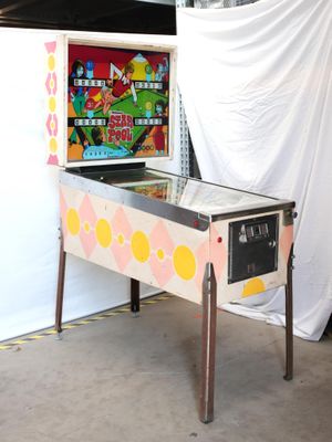 a pinball machine in a room with a white curtain